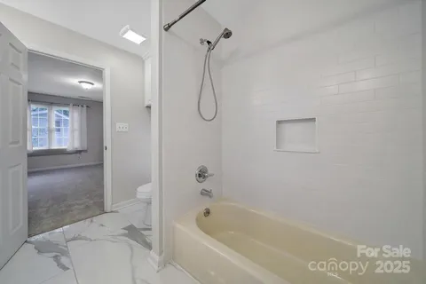a bathroom with a granite countertop bathtub shower and toilet