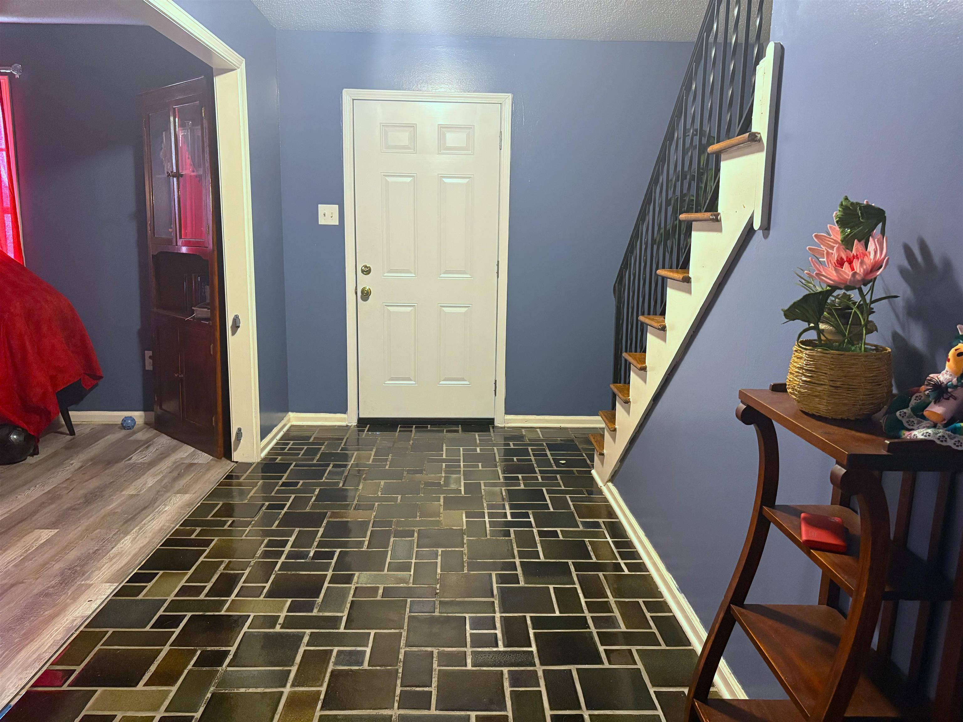 4009 Tessland Road Memphis, TN 38128 - Photo 5 of 16 Entryway featuring patterned tile flooring, a white paneled door, and a staircase with wood treads and black metal balusters