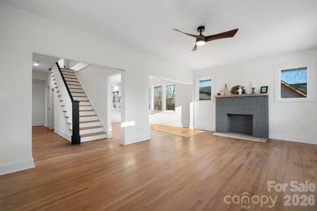 a view of an empty room with wooden floor and a ceiling fan