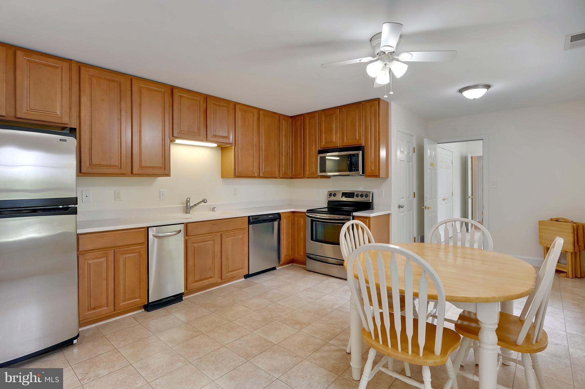 2816 Stinnett Road Huntingtown, MD 20639 - Photo 21 of 27 a kitchen with stainless steel appliances granite countertop a sink dishwasher a stove a refrigerator with a dining table and chairs