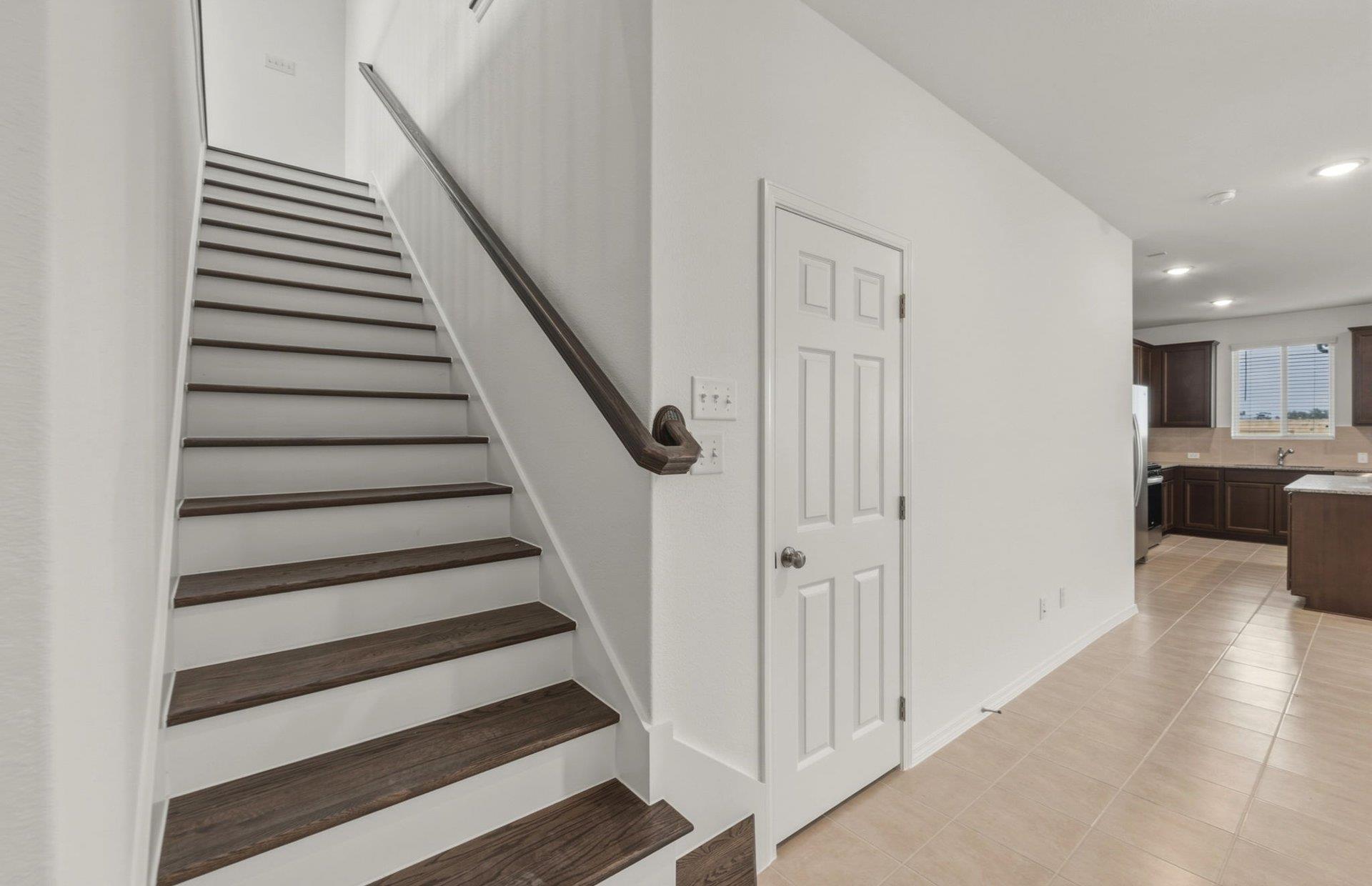 545 Henry Milton Road Georgetown, TX 78626 - Photo 7 of 33 An open entryway connects the modern staircase and tiled hallway to the kitchen beyond.