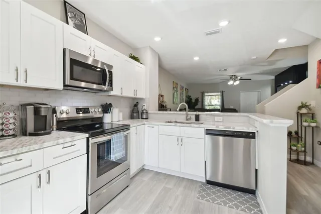 a kitchen with stainless steel appliances granite countertop a sink a stove top oven and white cabinets