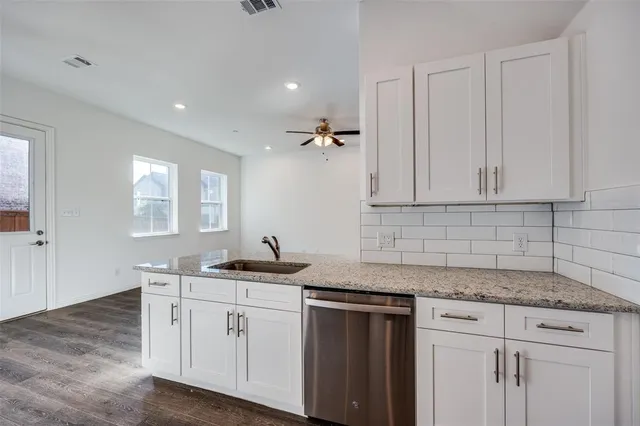 a kitchen with a sink dishwasher and white cabinets