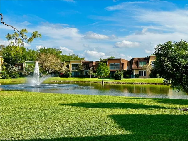 a view of swimming pool with lawn chairs and large trees