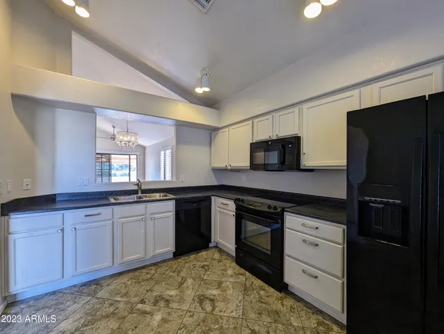 a kitchen with granite countertop a stove a sink and a refrigerator