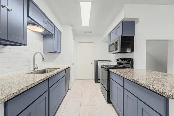 a kitchen with stainless steel appliances granite countertop a sink a stove and a wooden cabinets