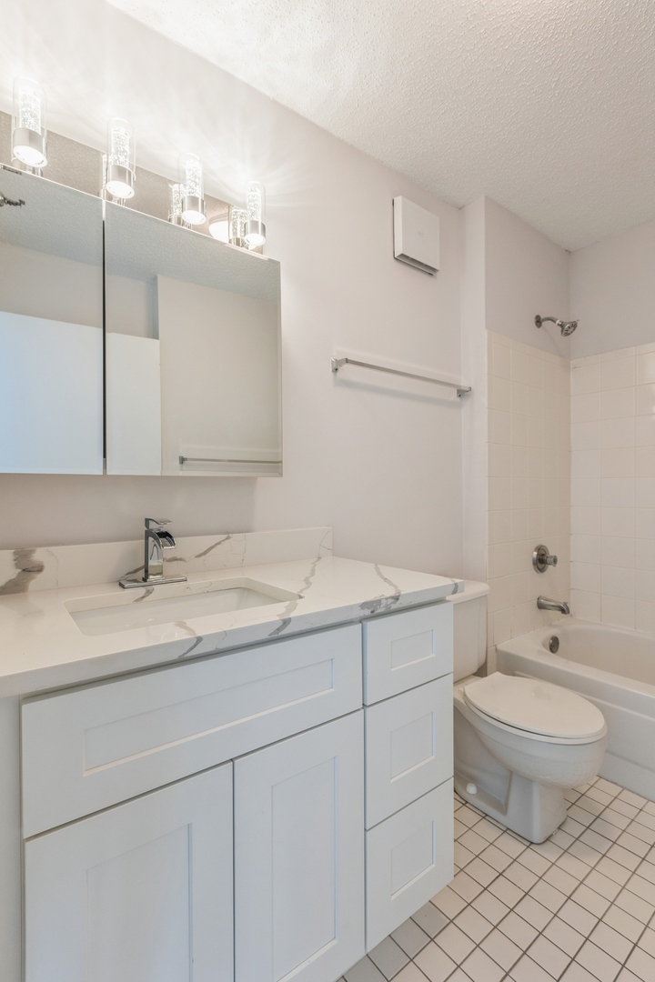 111 West Maple Street, Unit 3311 Chicago, IL 60610 - Photo 7 of 15 a bathroom with a granite countertop sink a toilet and a mirror