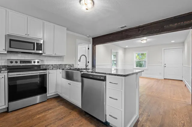 a kitchen with stainless steel appliances granite countertop a stove a sink and a microwave