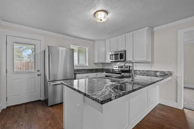 a kitchen with granite countertop a refrigerator stove and microwave