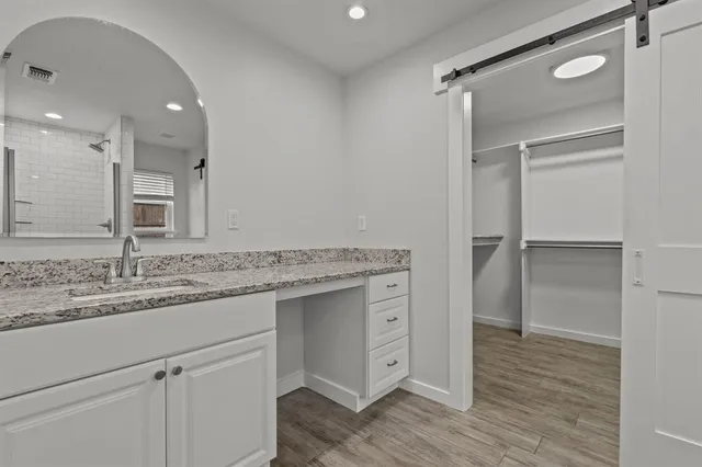 a bathroom with a granite countertop sink mirror and cabinets