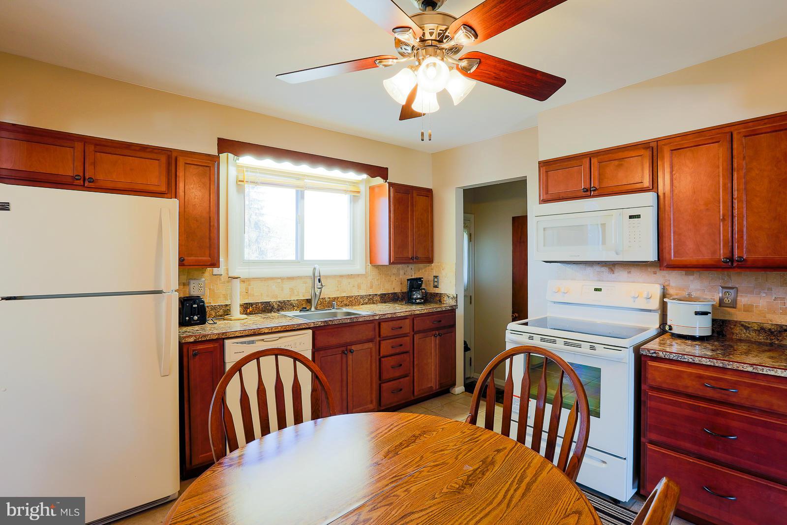 3834 Cherrybrook Road Randallstown, MD 21133 - Photo 12 of 30 a kitchen with a refrigerator a stove sink cabinets and a dining table