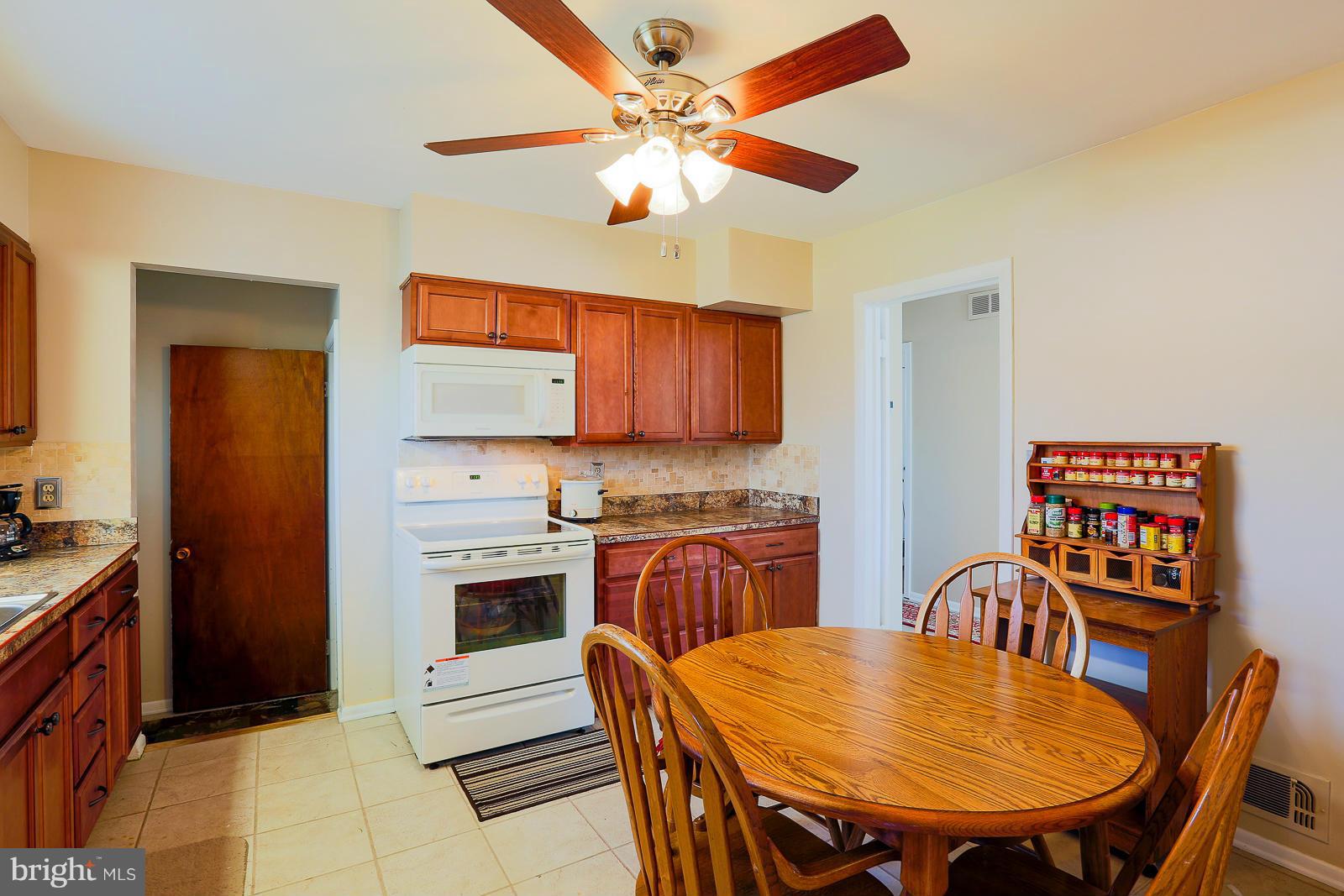 3834 Cherrybrook Road Randallstown, MD 21133 - Photo 10 of 30 a kitchen with stainless steel appliances granite countertop a stove a refrigerator a dining table and chairs with wooden floor