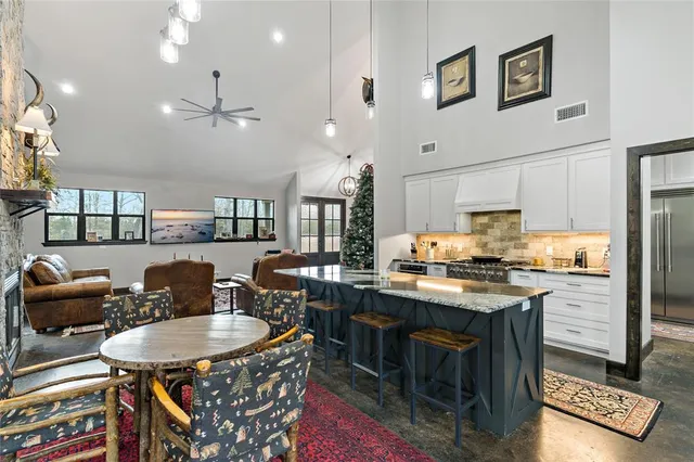 a kitchen with stainless steel appliances granite countertop a stove a refrigerator a kitchen island a dining table and chairs