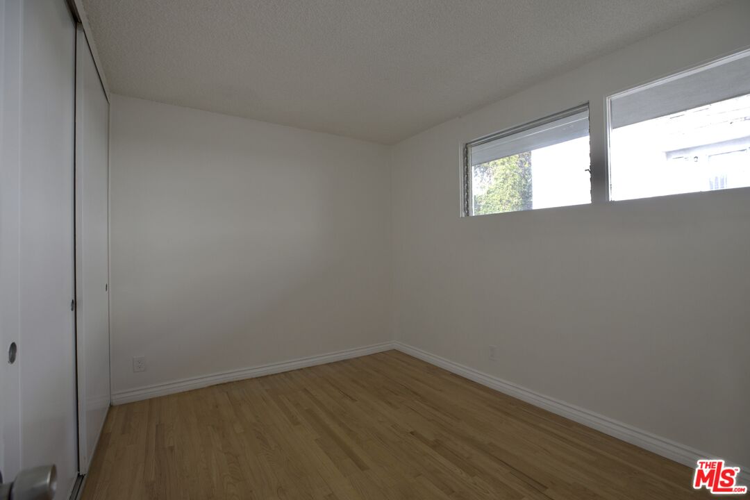 11131 Rose Avenue, Unit 13 Los Angeles, CA 90034 - Photo 9 of 17 a view of an empty room with wooden floor and a window