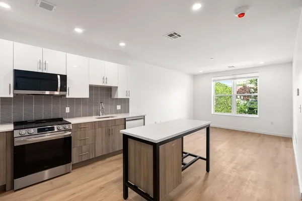 a kitchen with stainless steel appliances granite countertop a stove a sink dishwasher a microwave oven and a refrigerator with wooden floor