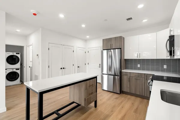 a kitchen with stainless steel appliances granite countertop a refrigerator a sink dishwasher and a stove with wooden floor