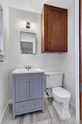 a bathroom with a toilet a sink a mirror and vanity