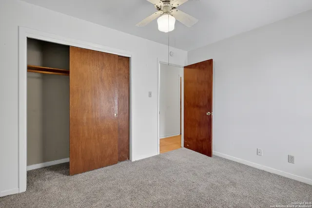 an empty room with closet and a chandelier fan