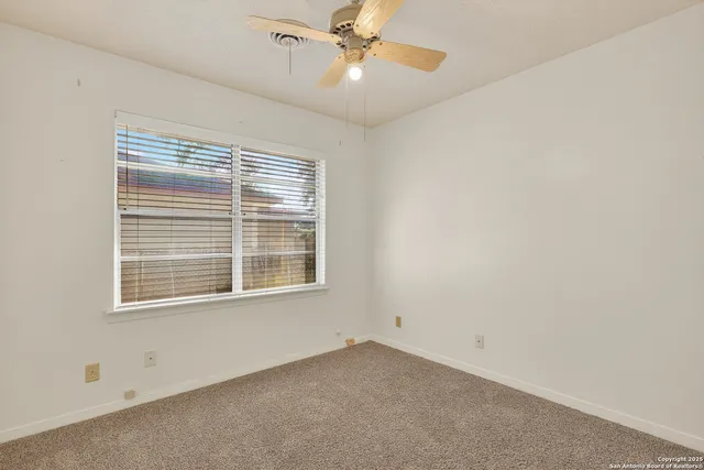 an empty room with a window and a fan