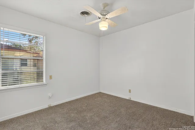 an empty room with a window and a fan