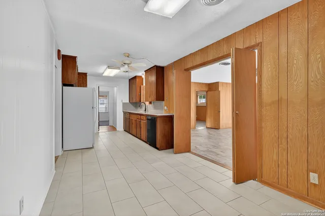 a view of a kitchen with refrigerator and an empty room