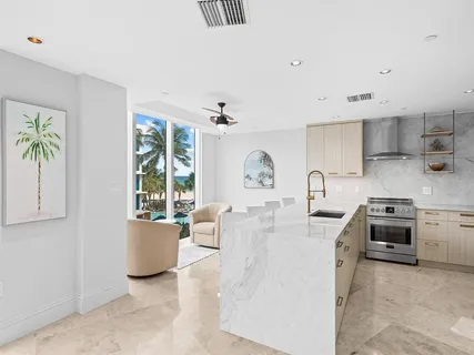 a large white kitchen with stainless steel appliances a stove a sink a desk and chair