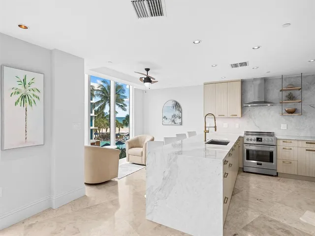 a large white kitchen with stainless steel appliances a stove a sink a desk and chair