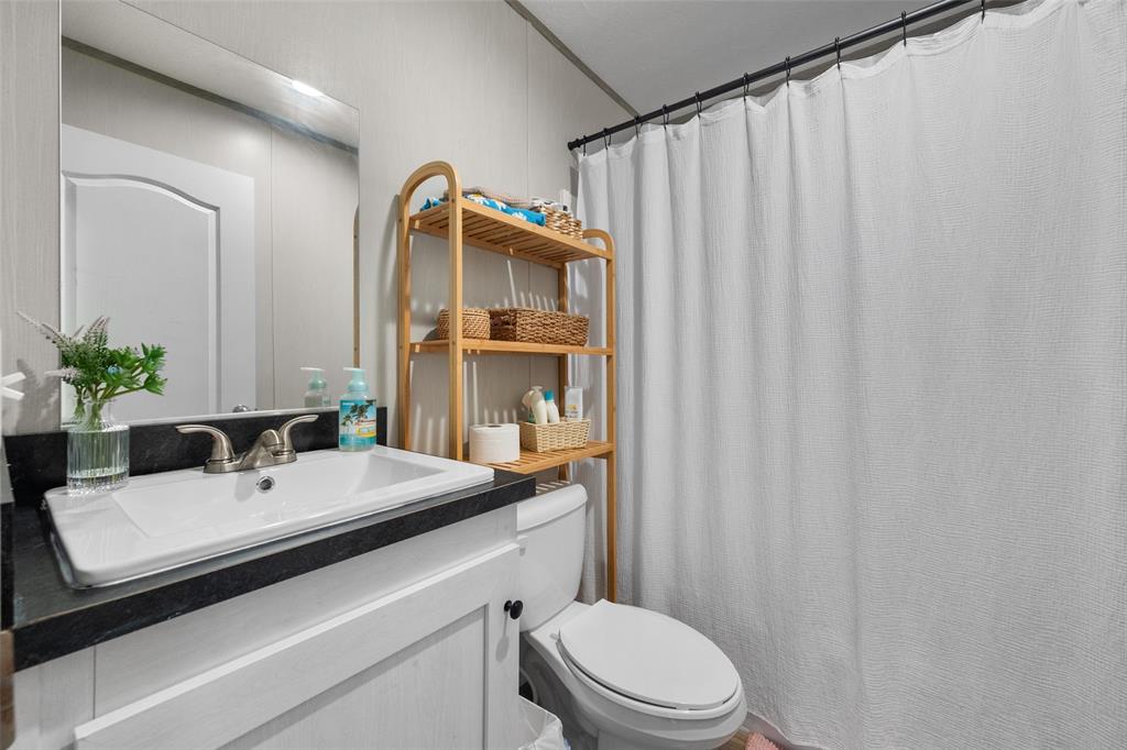 421 Garitty Street Frost, TX 76641 - Photo 21 of 25 a bathroom with a sink a toilet and shower curtain