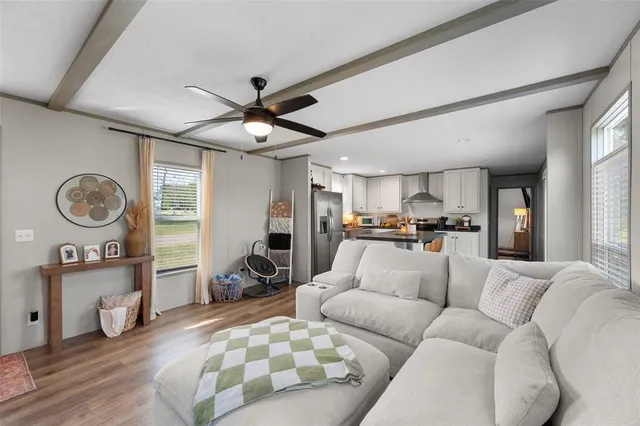 a living room with furniture a rug kitchen view and a large window