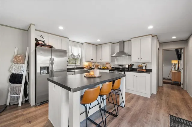 a kitchen with stainless steel appliances granite countertop a refrigerator a sink and a stove top oven