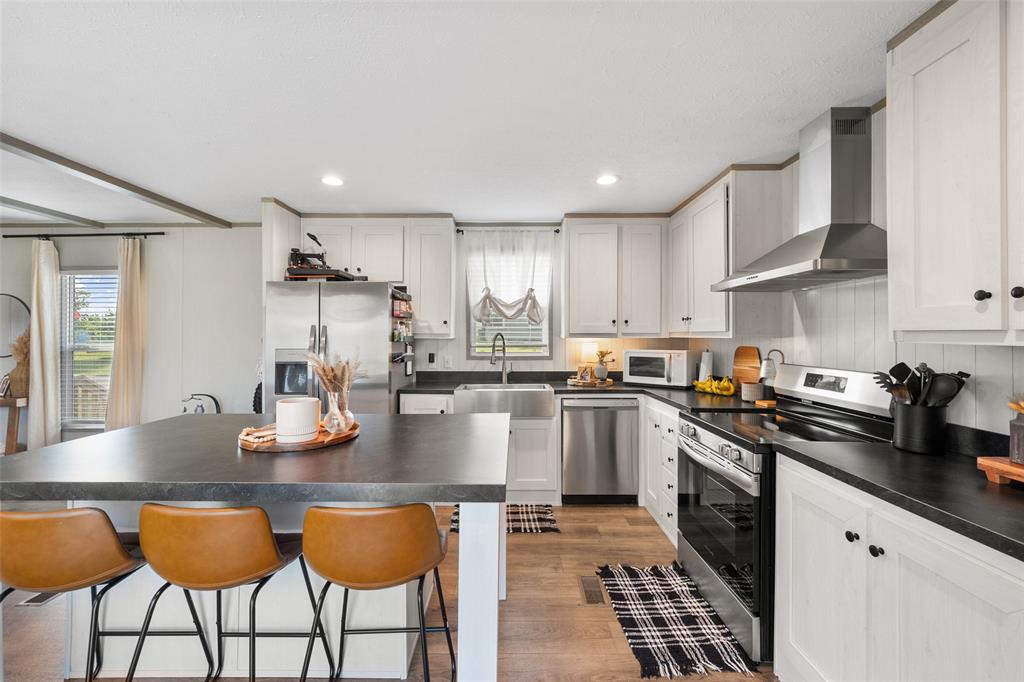 421 Garitty Street Frost, TX 76641 - Photo 10 of 25 a kitchen with stainless steel appliances granite countertop a sink dishwasher a refrigerator and white cabinets with wooden floor
