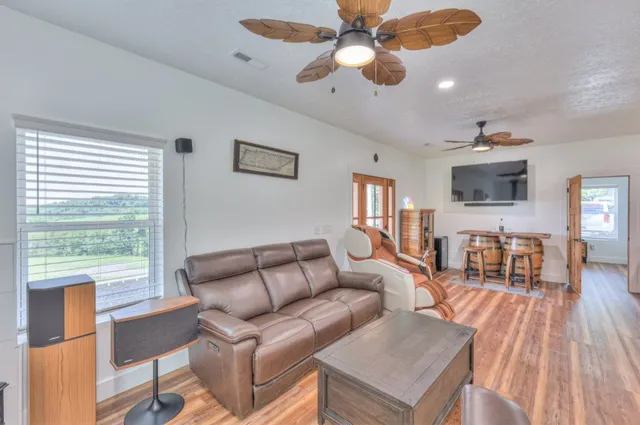 a living room with furniture a ceiling fan a fireplace and a large window