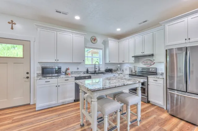 a kitchen with granite countertop white cabinets stove and refrigerator