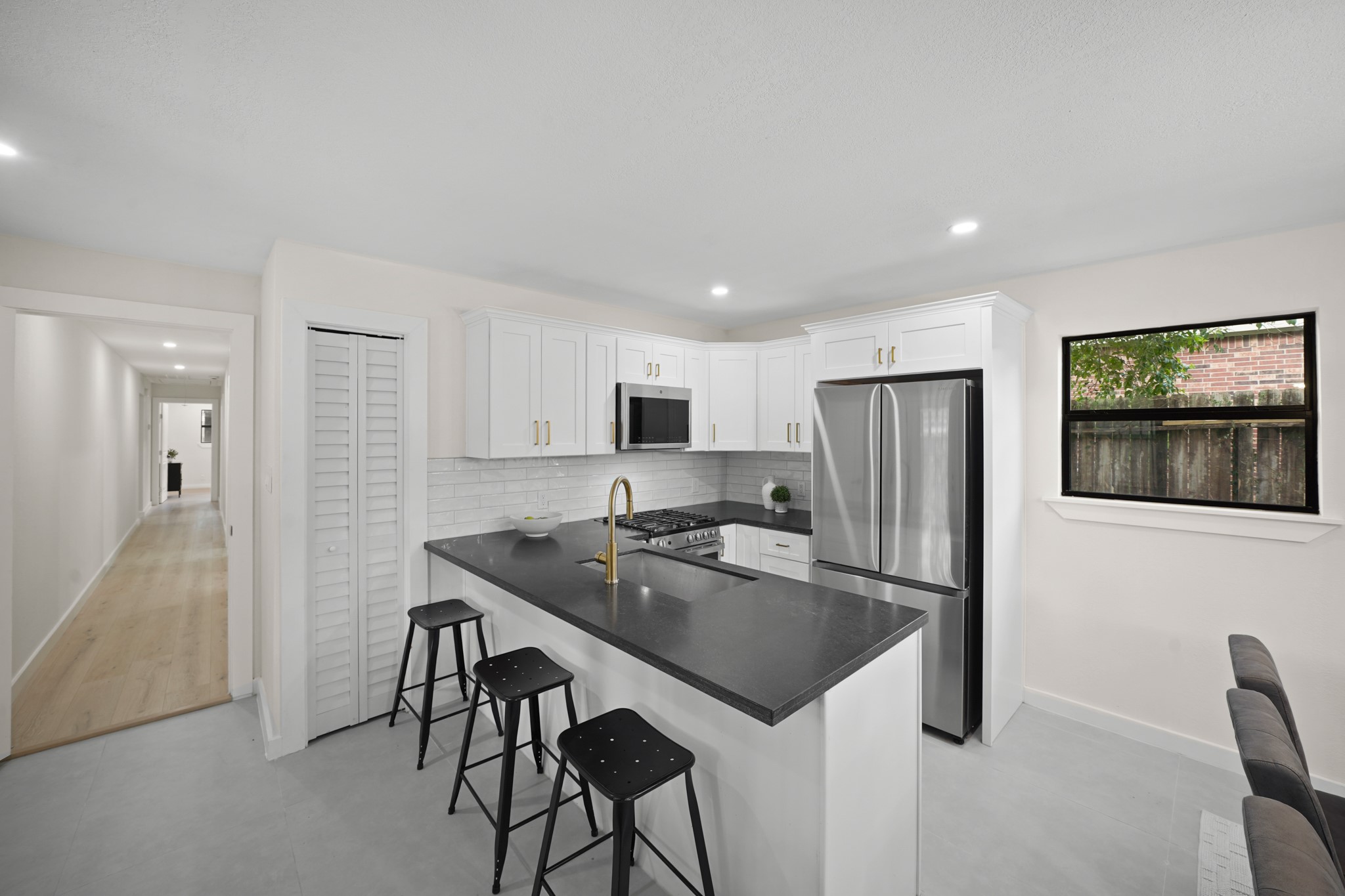 4813 Hummingbird Street Houston, TX 77035 - Photo 22 of 50 a kitchen with stainless steel appliances granite countertop a refrigerator a stove a sink a microwave a dining table and chairs with wooden floor