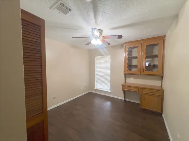en empty room with windows and ceiling fan