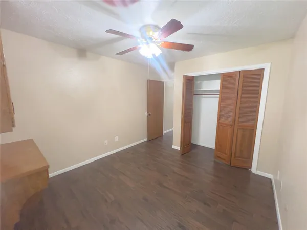 an empty room with wooden floor fan and window