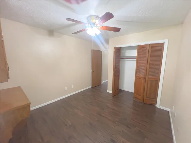 an empty room with wooden floor fan and window