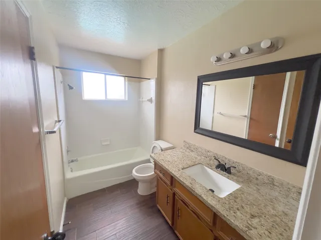 a bathroom with a granite countertop sink toilet mirror and bathtub