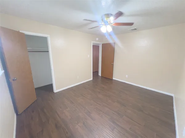an empty room with wooden floor fan and window