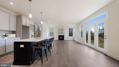 a kitchen with stainless steel appliances granite countertop a refrigerator a sink dishwasher a stove and a dining table with wooden floor