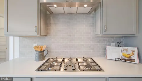a kitchen with granite countertop a stove a sink and a white wooden cabinets