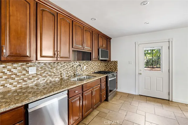 a kitchen with stainless steel appliances granite countertop a stove a sink and a microwave