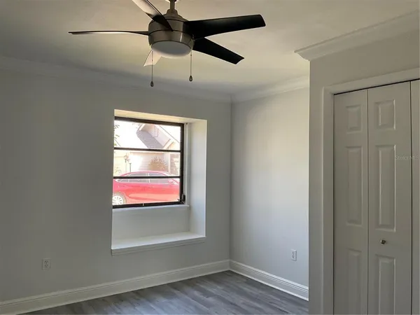 an empty room with wooden floor fan and windows
