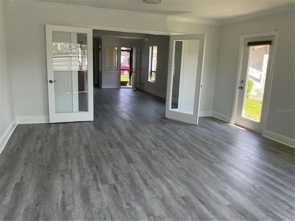 a view of an empty room with wooden floor and a window