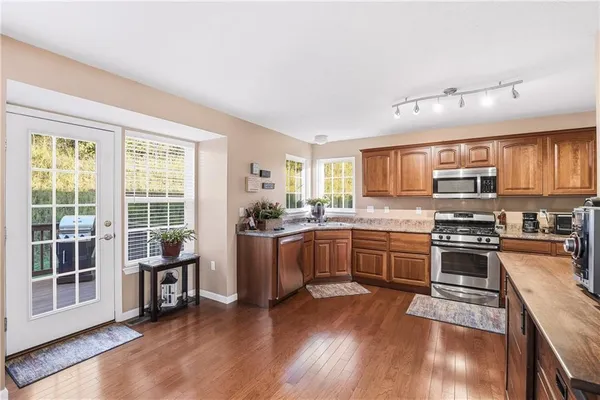 a kitchen with granite countertop a stove top oven a sink dishwasher a dining table and chairs with wooden floor