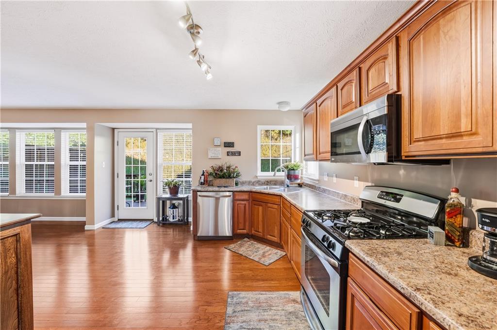 104 Broadstone Drive Mars, PA 16046 - Photo 6 of 30 a kitchen with stainless steel appliances granite countertop a stove top oven a sink dishwasher a dining table and chairs with wooden floor