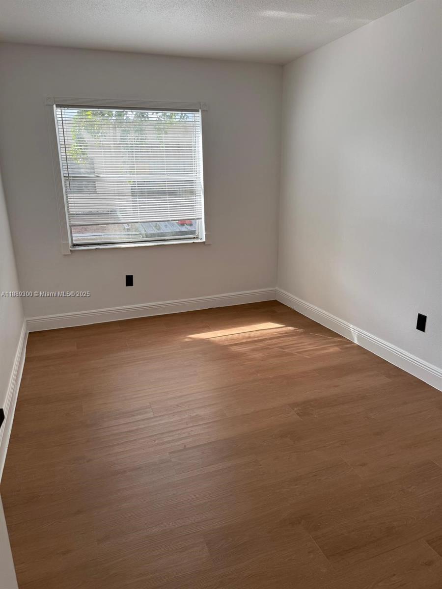 4163 Southwest 66th Terrace, Unit 108 Davie, FL 33314 - Photo 14 of 15 an empty room with wooden floor and windows
