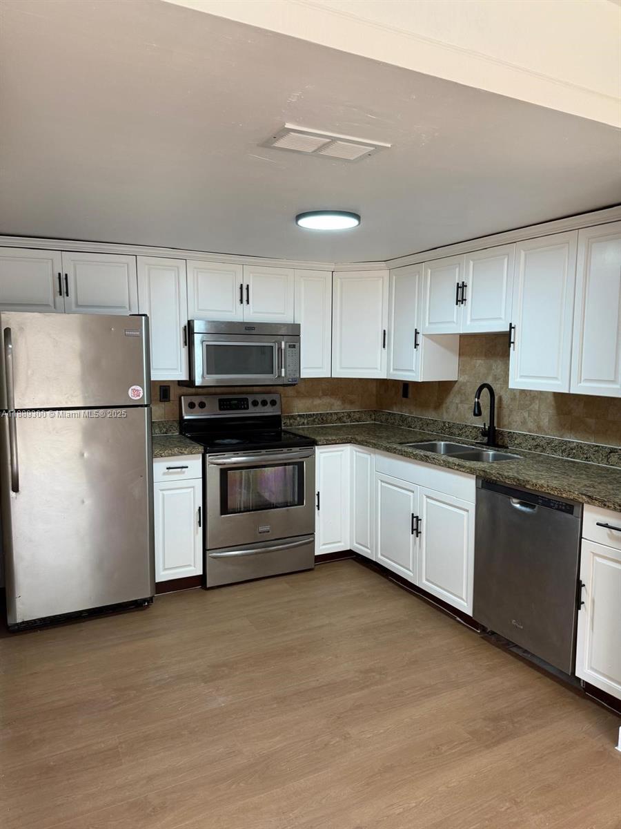 4163 Southwest 66th Terrace, Unit 108 Davie, FL 33314 - Photo 5 of 15 a kitchen with stainless steel appliances granite countertop a refrigerator and a stove top oven