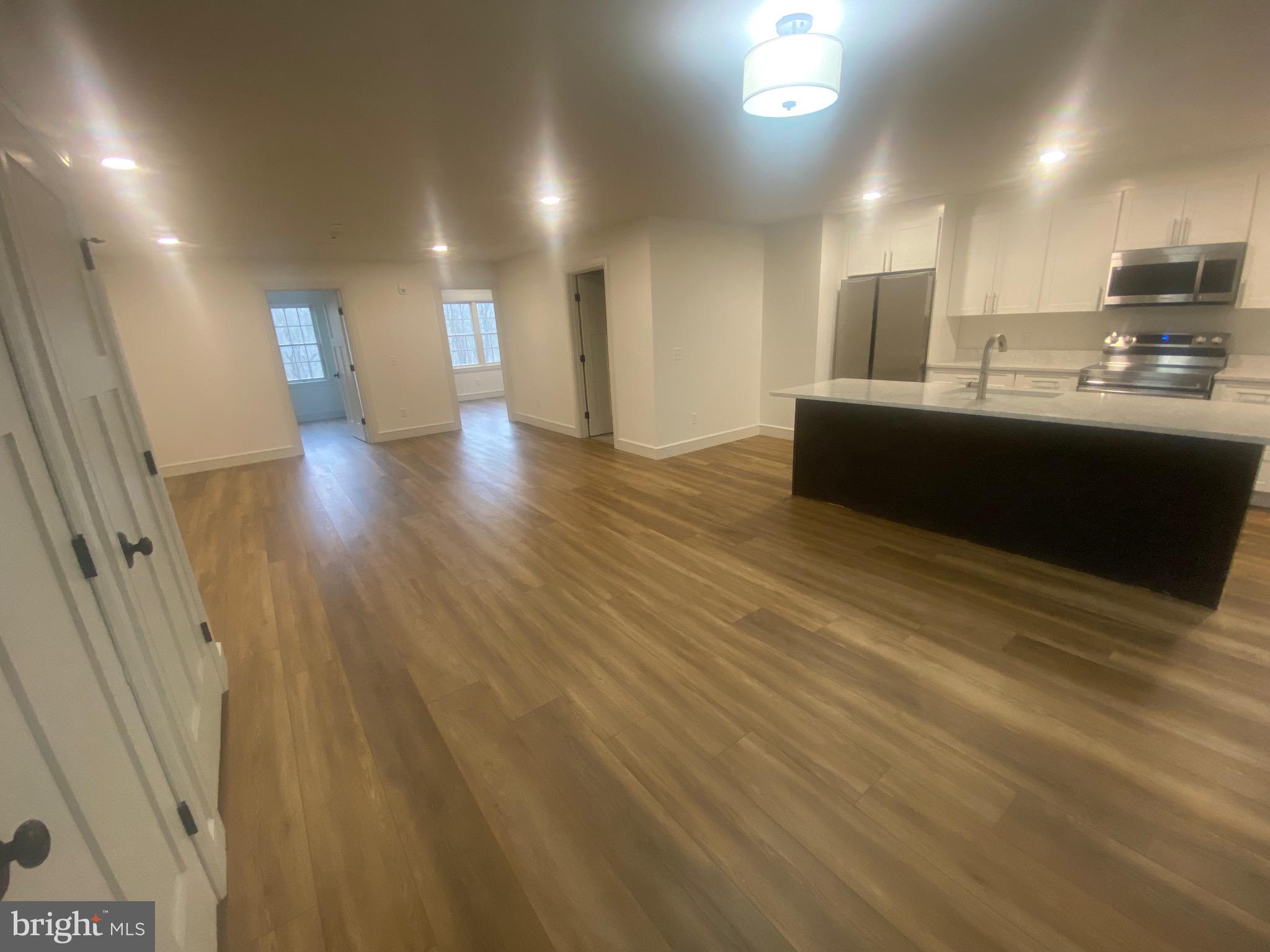 1087 Mt Tom Road, Unit 204 East Stroudsburg, PA 18301 - Photo 3 of 17 a view of a kitchen with kitchen island a sink wooden floor and a counter top space