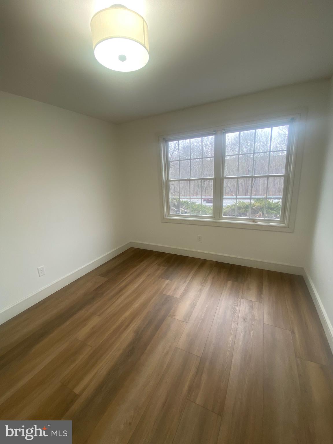 1087 Mt Tom Road, Unit 204 East Stroudsburg, PA 18301 - Photo 9 of 17 an empty room with wooden floor and windows